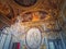 The War Room, Palace of Versailles, France. Chandelier hangs out of the golden painted ceiling and the stucco medallion of Louis