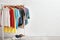 Wardrobe rack with stylish clothes and shoes near brick wall indoors.