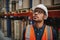 Warehouse male supervisor in uniform and helmet thinking standing in factory looking away