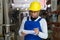 Warehouse male worker in protective helmet and overalls counts the quantity of goods and writes in notebook