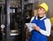 Warehouse male worker in protective helmet and overalls counts the quantity of goods and writes in notebook