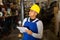 Warehouse male worker in protective helmet and overalls counts the quantity of goods and writes in notebook