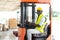 Warehouse man worker driver forklift. warehouse worker driver stacking card boxes by forklift in warehouse store. African American