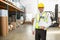 Warehouse manager wearing hard hat holding clipboard