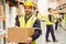Warehouse worker smiling at camera carrying a box