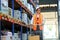 Warehouse worker walks between the shelves with a trolley.