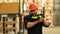 Warehouse workers in safety uniform working in warehouse full of tall shelves with goods in cardboard boxes