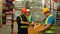 Warehouse workers in safety uniform working in warehouse full of tall shelves with goods in cardboard boxes