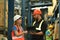 Warehouse workers in safety uniform working in warehouse full of tall shelves with goods in cardboard boxes