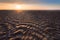 Warm afternoon sun rays on a beach at low tide with sand patterns in Taiwan, under blue sky