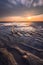 Warm afternoon sun rays on a beach at low tide in Taiwan with sand patterns and clouds passing