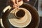 Warm closeup of female hands shaping clay on pottery wheel while making ceramics in sunlit workshop