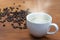 warm coffee cup and beans on wood