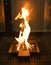 A warm flame of a wood-burning fireplace with panoramic glass in the house