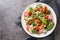 Warm french salad with bacon, spinach, roquefort cheese, walnuts, tomatoes, basil and garlic close-up in a plate. Horizontal top