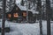 Warm glowing windows from a wooden cabin in the wintery forest