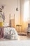 Warm lamp light in a soft colors bedroom interior with a bed dressed in bedding, cushions and blanket. Painted material art on the