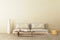 Warm neutral style interior mockup with low sofa, ceramic jug, side table on empty concrete wall background. 3d rendering