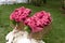 Warm pink blankets rolled up in the form of roses in a large basket for guests at an outdoor wedding party. Individual dance white