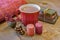 Warm red mug of hot chocolate on rustic wooden table, cozy autumn blanket and fall candles