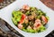 Warm salad with chicken liver, tomatoes, lettuce leaves, broccoli on wooden table.