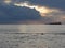 Warm sea sunset with cargo ship and a small fishing boat at the horizon . Giants cumulonimbus clouds are in the sky. Tuscany, Ital