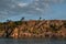 Warm sunset on Lake Baikal, Rocky red stones shore with cliffs, reflection in ripples