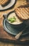 Warming celery cream soup and toast over linen tablecloth, close-up