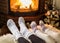 Warming and relaxing near fireplace. Woman and child feet in fro