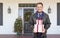 Warmly Dressed Man Holding Gifts Standing on Christmas Decorated Front Porch