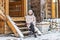 Warmly dressed young woman posing on the porch of a wooden house in the village. Winter holidays in the countryside