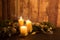 The warmth of the Christmas concept: three candles lit with cross screen stars effect on a dark wooden table with pine branches,