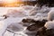 Warmth of orange sunlight on ice covered rocks