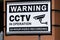 Warning CCTV in operation 24 hour video recording sign on brick wall