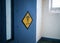 Warning danger biohazard diamond shaped sticker on prison cell blue open door sunlight in window of high security run down jail