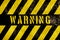 Warning danger sign text with yellow and dark stripes painted over concrete wall facade texture background.