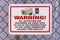 Warning security camera sign on a chain link fence