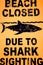 Warning sign: Beach closed due to shark sighting.