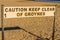 Warning sign stating caution keep clear of groynes, landscape