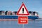 Warning sign with the text `Trade war` in front of a huge container ship.