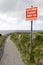 Warning sign among wild flowers along a cliff path