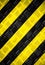 Warning sign yellow and black stripes painted over steel checker diamond plate on the floor or wall as texture background.