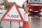 Warning Traffic Sign On Flooded Road With Fire Engine