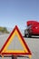 Warning triangle in front of broken down red sports car at side of road