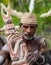 Warrior Asmat tribe sits and carves a ritual statue.
