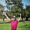 That was the best shot all week. a cheerful young male golfer lifting up his hands in success of playing a good shot