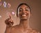 Was I was supposed to hold out darling. Portrait of a young attractive woman posing with bubbles against a brown