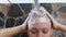 Wash brunette hair on woman`s head with shampoo in shower