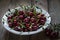 A washed cherry with water drops in a white plate on a wooden table.