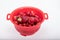 Washed fresh ripe strawberries in a red plastic strainer.